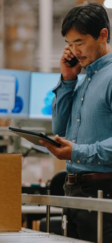 man talking on phone and looking at ipad